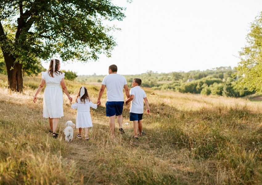A family walking through a field with a dog